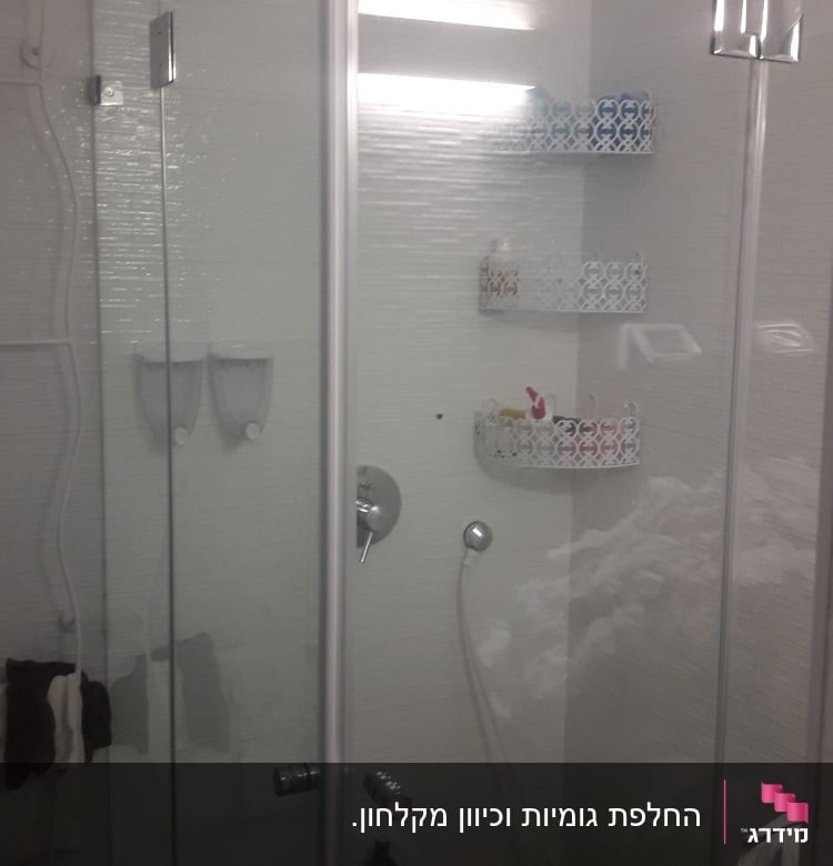 מקלחון זכוכית עם מדפים ומוצרים לטיפוח